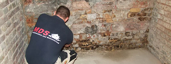 Fachmann von MDS Bautenschutz Steinbach bei Frankfurt am Main prüft feuchten Keller vor der Hausabdichtung